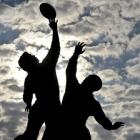 The sun rises behind a statue of rugby players reaching for the ball, outside Twickenham in west...