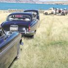 The wedding cars wait at the photo stop overlooking Lake Benmore while Joseph Cameron and...