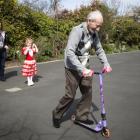 Tom Galway rides the scooter watched by his granddaughter Jan and his great-granddaughter...