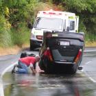 Two members of the public inspect a car after it rolled on Portobello Rd, near Glenfalloch...