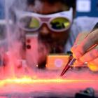 University of Otago physicist Dr Jevon Longdell examines a transparent silicate crystal...