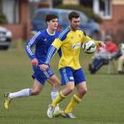 University player Elliott Martin (yellow) plays the ball as Mosgiel's Hamish Cotter looks to ...