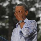 US President Barack Obama wipes rain off his face during heavy rainfall at a campaign rally in...