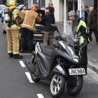 Vincent Maffey looks under the bonnet of his car with firefighters in Moray Pl yesterday. Photo:...