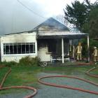 Volunteer firefighters try to save this Kaitangata home yesterday  morning. Police and the Fire...