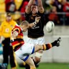 Waikato halfback David Bason has his kick charged down by Wellington lock Jeremy Thrush during...