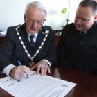 Waitaki Mayor Alex Familton signs the Otago and Southland Regional Charter HMNZS Otago, watched...