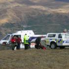 Wanaka LandSar volunteers escort an injured Irish tramper (at left) from the rescue helicopter...