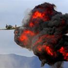 A Harvard flies past a fireball from a mock airfield attack at Warbirds over Wanaka. Photo by...