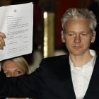 WikiLeaks founder Julian Assange holds up a court document for the media after he was released on...