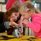 Xanthe White helps Evangeline Clarke (3) plant a broad bean in a recycled plastic bottle during a...