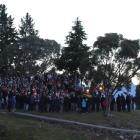 A crowd gathers on the rocky headland and cenotaph flagpole at Lake Hawea for an Anzac Day dawn...