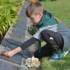 Will Moyle (7), of Green Island, places a posy on a returned serviceman’s grave during an Anzac...