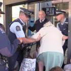 Police help an older woman to negotiate  climate change protesters blocking the entrance to an...