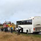 A truck lines up to tow a bus stopped near Clinton after an engine fire, as passengers wait for a...