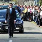 A guard of honour stretches down Horse Range Rd as the family of Andrew Grubb walk behind the...