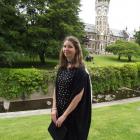 Brittany Travers outside the University of Otago clocktower building in her graduation gown....