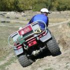 A rider uses his weight to balance his quadbike as he negotiates an off-camber slope. Photo from...