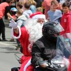 Santa waves to the crowd as he rides a motorcycle, instead of his traditional reindeer and sleigh...