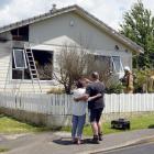 Steve Wedlock is comforted by a woman as firefighters work in his Sawyers Bay home yesterday....