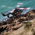 A helicopter hovers over rescuers attending to one of two kayakers trapped on rocks at Nugget...