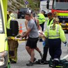 St John paramedics and AJ Hackett Bungy staff carry one of the motorcyclists to an ambulance...