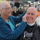 Kevin Bayne lets his wife Coleen shave his head as a show of support after she survived blood...