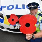 Dunedin Central community Constable Kerrin Williams shows off the large poppies which adorn some patrol cars in the city. Photo by Peter McIntosh.