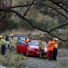 Emergency services personnel survey the scene after pulling a car out of the Arrow River...