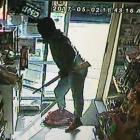 A masked man, armed with a rifle, is captured by a security camera entering the On the Spot Halfway Bush Convenience Store yesterday. The man fled with cash and tobacco. Photo supplied.