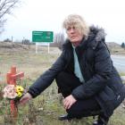 Alexandra woman Kate Jensen lays flowers on a cross at the intersection where her ex-husband was...