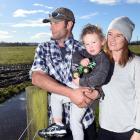 Henley dairy farmers Reon Hamilton and his fiance Emma Keene with son Cooper (2) at a flood...