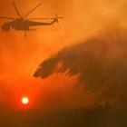 A firefighting helicopter makes water drop as a wildfire burns near the village of Metochi. Photo...