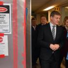 Prime Minister Bill English walks with charge nurse Mary Molloy past an asbestos warning sign at...