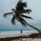 Tourists walk along a beach with heavy clouds caused by the proximity of tropical storm Franklin...