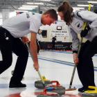 Working together to sweep their stone into the house are the New Zealand junior mixed-doubles...
