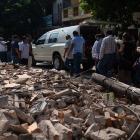 People walk by debris during a funeral ceremony held for a person that died in the earthquake in...