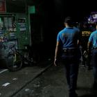 Policemen from Caloocan Police District patrol a dimly lit alley at a residential district in...