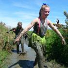 Taieri College pupils Poppy Kirk (front) and Briana Day make their way out of the mud creek...