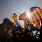 People hold on to Catalan separatist flags on top of an air vent during a demonstration two days...
