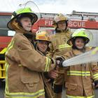  Charitable youngsters Taylor McLean, second from left, and her sister Kate try using a fire hose...