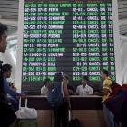 Passengers ask staff about their flights near the flight screen at Ngurah Rai airport. Photo:...