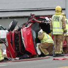 Firefighters work  to free two people trapped in a vehicle involved in a two-vehicle crash at...