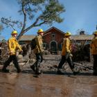 Rescue workers enter properties to look for missing persons after a mudslide in Montecito,...