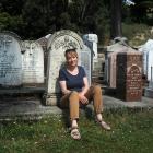 New Kaitangata resident Denise Dent sits in front of headstones at the local cemetery, including...