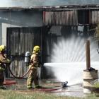 Firefighters dampen down a fire that took hold in the workshop of this Arthurs Point home...