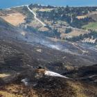 A lone firefighter stands on Mt Alpha looking down at the smouldering land. Photos: Sean Nugent...