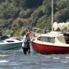 Brent Young (left, in power boat) prepares to tow a stricken yacht off a mud-bed near the...