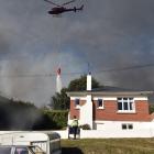 A helicopter equipped with a monsoon bucket puts out a fire on a Mulford St property during last...