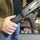 A bump stock device, (left) that fits on a semi-automatic rifle to increase the firing speed,...